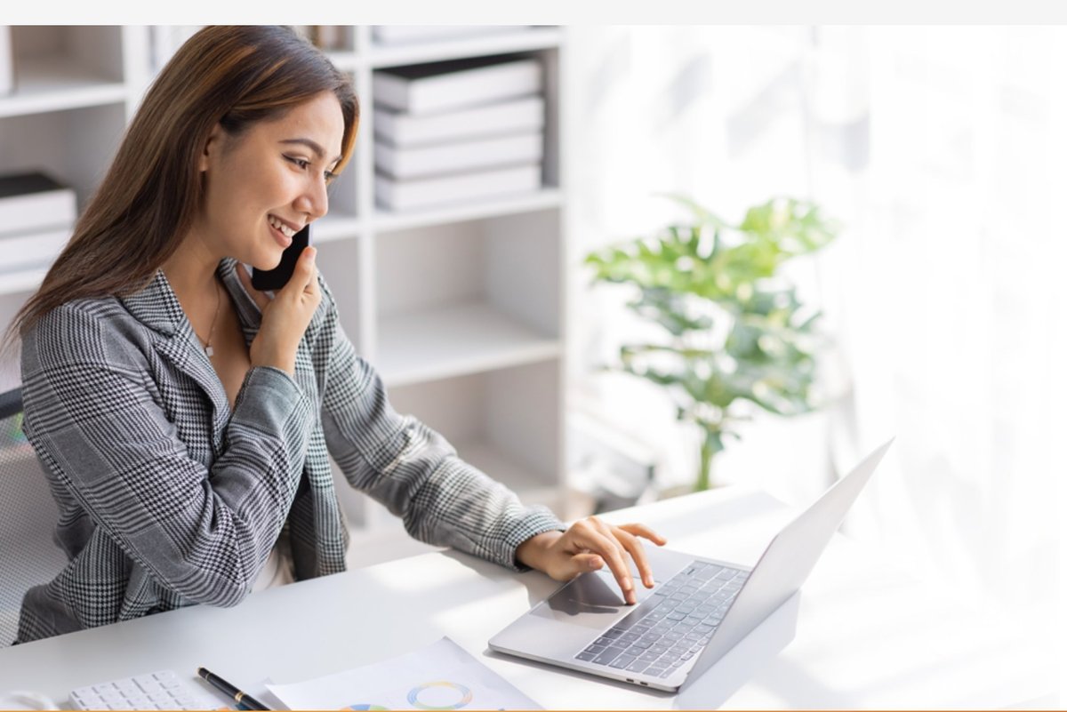 Support agent smiling on a phone call while working at her laptop